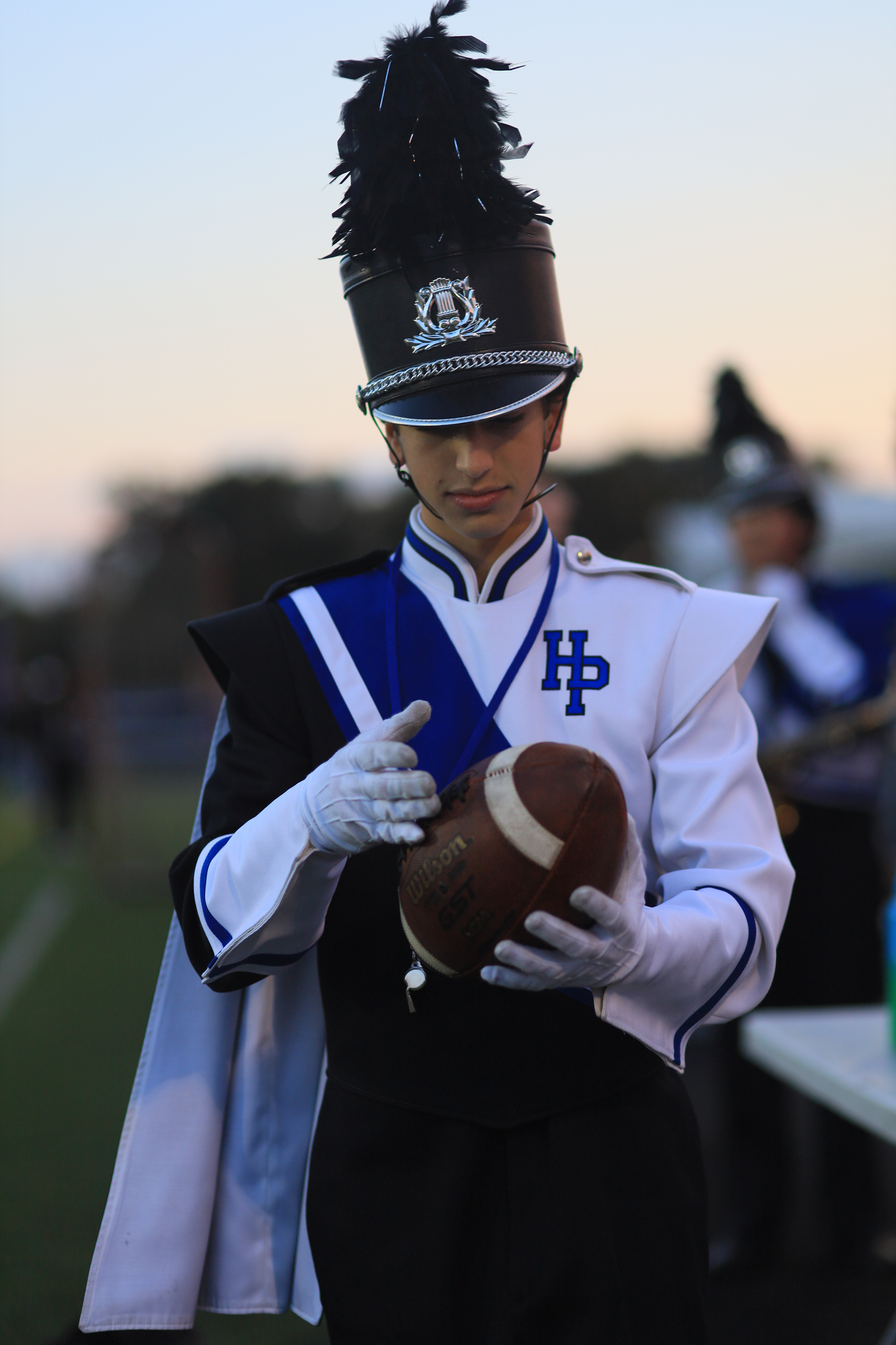Contemplating a football in drum major uniform