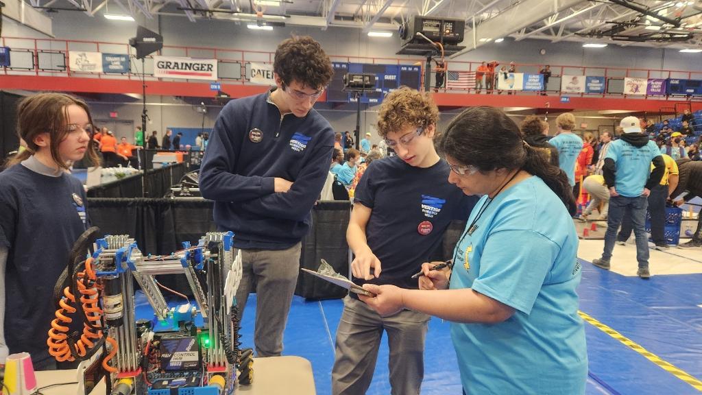 Pointing at a clipboard as a robot is inspected