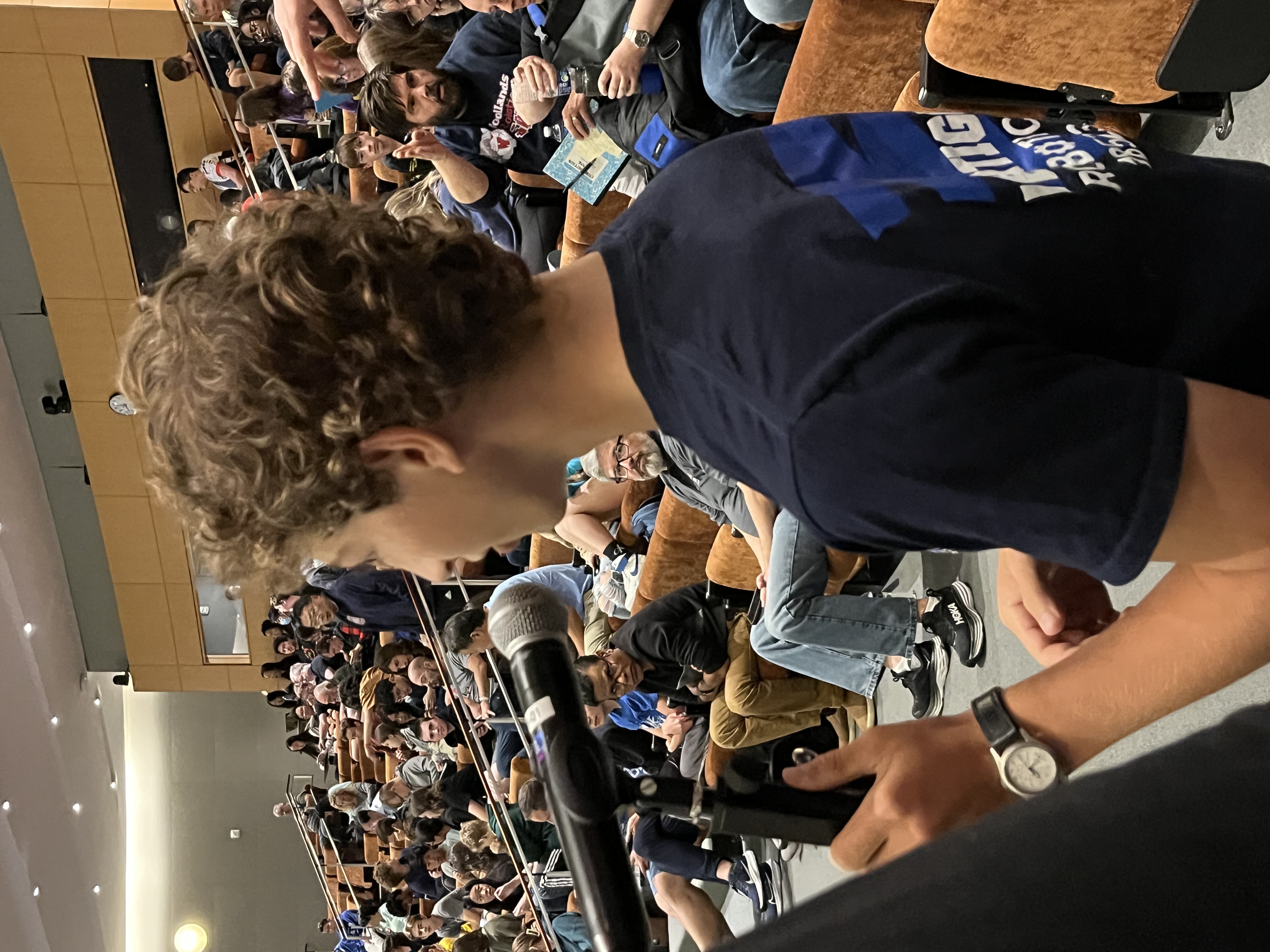 Speaking into a microphone in front of a crowd